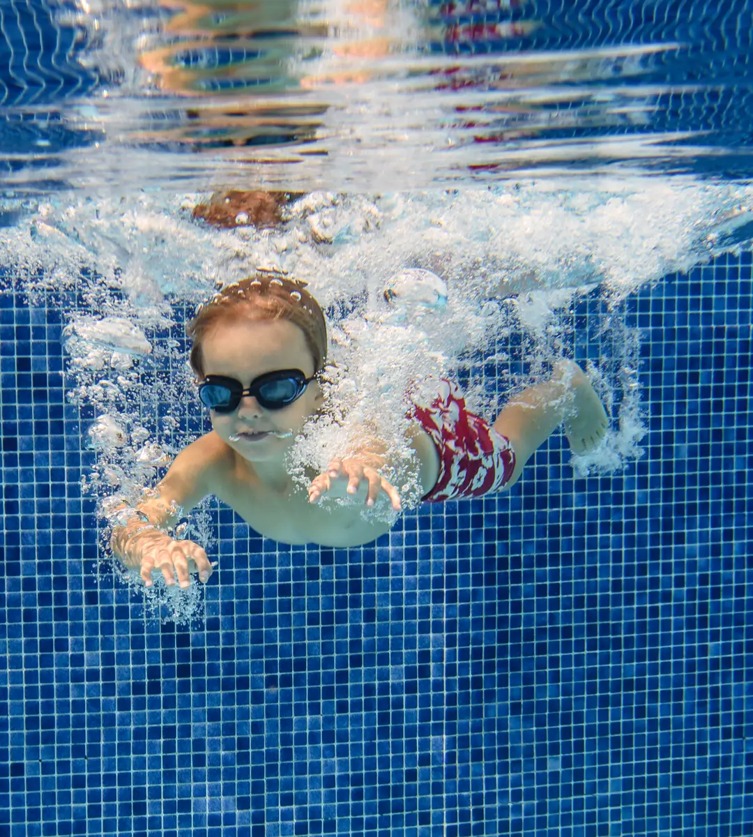 Copil înotând sub apă, cu ochelari de înot, în piscina Luxuria Centrum